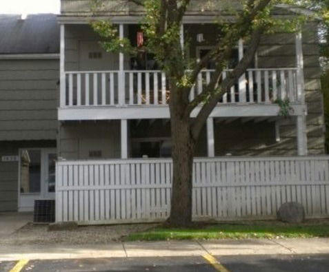Front view of a two-story residential building with balconies and a fenced area.