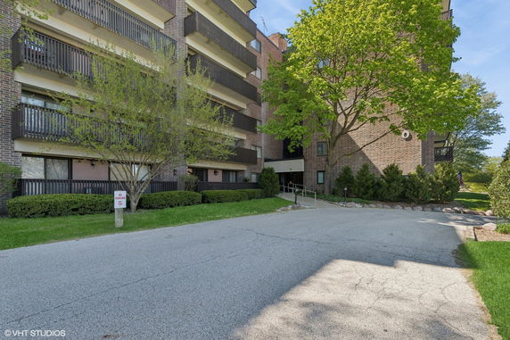 Front view of a multi-story apartment building with balconies and brick facade.