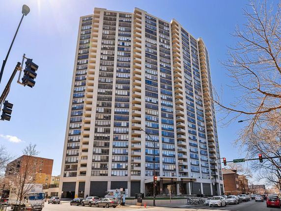 Front view of a tall residential building with multiple balconies.