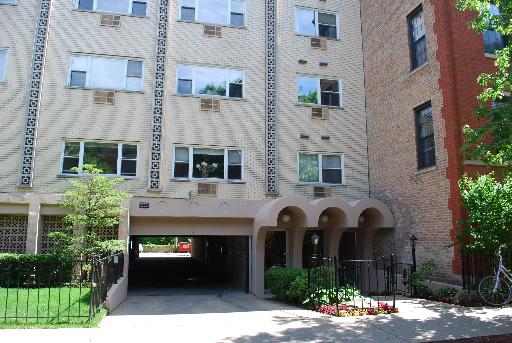 Front view of a multi-story residential building with an entrance driveway.