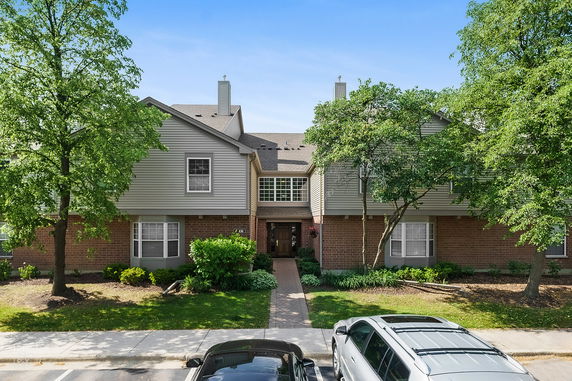 Front view of a multi-story residential building with a brick and panel exterior.