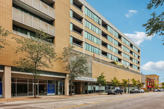 Front view of a multi-story building with a brick facade and large windows.