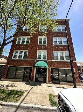 Front view of a four-story brick building with a green awning over the entrance.