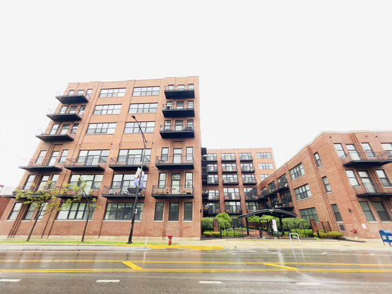 Front view of a multi-story brick apartment building with balconies.