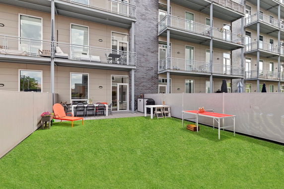 Front view of a multi-story building with balconies and outdoor seating area.