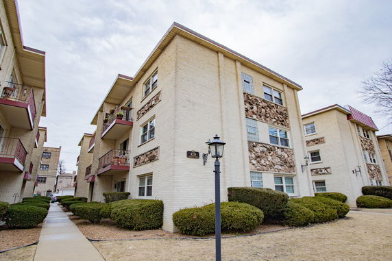 Front view of a multi-story apartment building with stone facade accents and balconies.