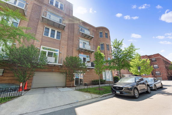 Front view of a multi-story apartment building with balconies and garage.