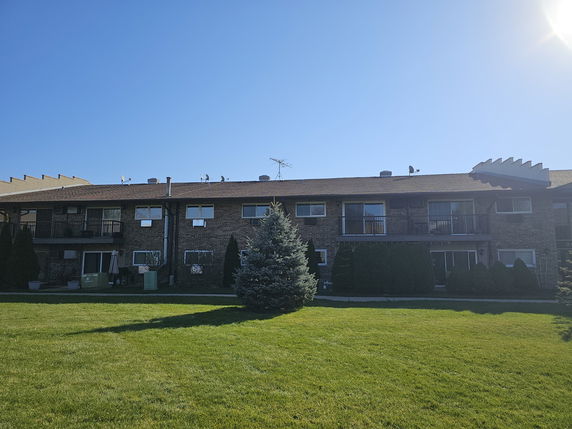 Front view of a two-story apartment building with balcony and lawn.