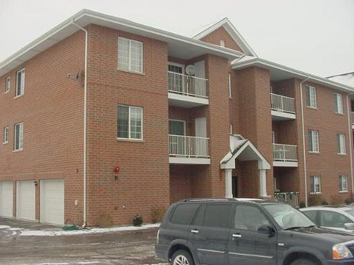 Front view of a three-story brick apartment building with balconies.