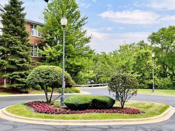 View of surrounding landscaped area with trees and street lamps near a brick building.