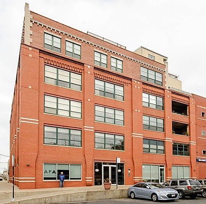 Front view of a multi-story brick building with large windows and a flat roof.