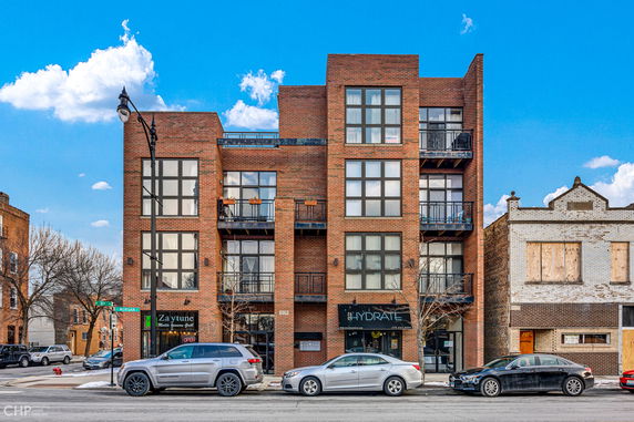 Front view of a multi-story brick building with large windows and balconies.