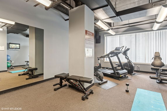 Interior of a gym with exercise equipment and large window.