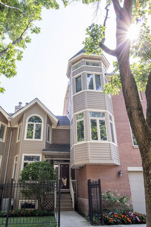 Front view of a multi-story house with bay windows and brick facade.