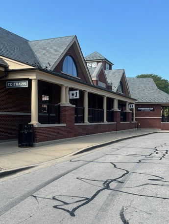 Front view of a brick building with gabled roofs and signage indicating direction to trains.