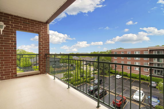 View from a balcony overlooking a parking area and surrounding buildings.