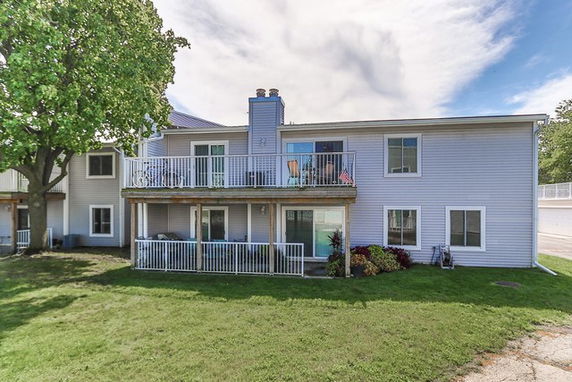 Front view of a two-story house with balconies and large windows.