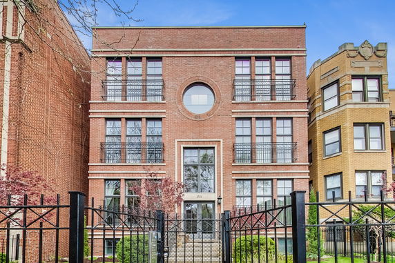 Front view of a multi-story brick building with large windows and decorative balconies.