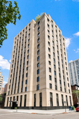 Front view of a tall, multi-story, rectangular building with multiple windows and a beige exterior.