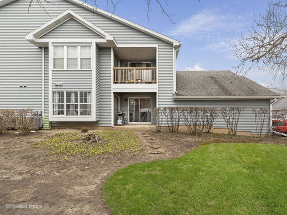Front view of a two-story house with a balcony and grey siding.