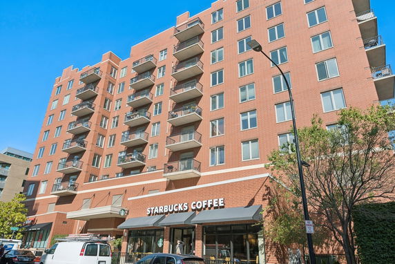 Front view of a multi-story brick building with balconies and a Starbucks Coffee shop on the ground floor.