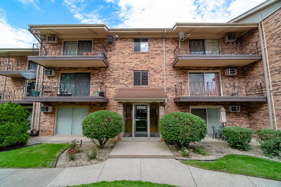 Front view of a brick three-story apartment building with balconies.