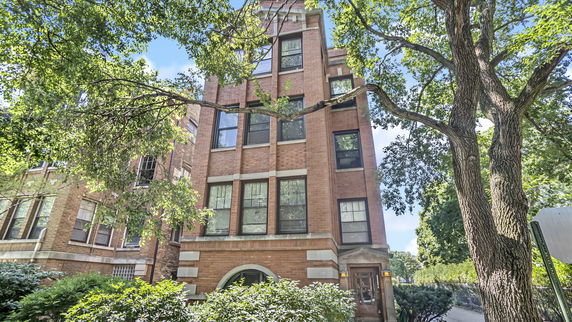 Front view of a multi-story brick building with large windows.