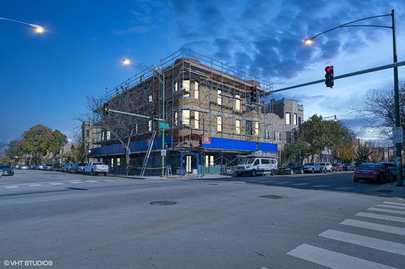 Street view of a building under renovation with scaffolding on its facade.