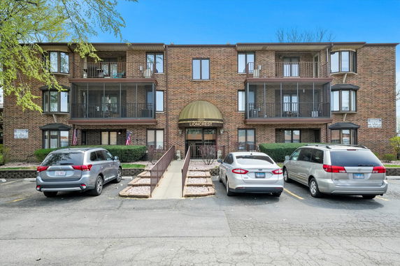 Front view of a multi-story brick apartment building with balconies.