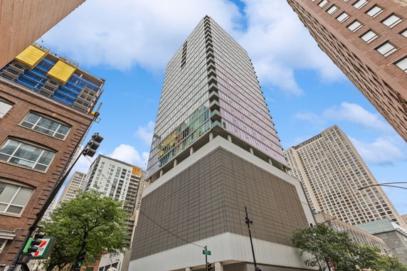 Front view of a tall modern building with a grid-like facade and reflective windows.
