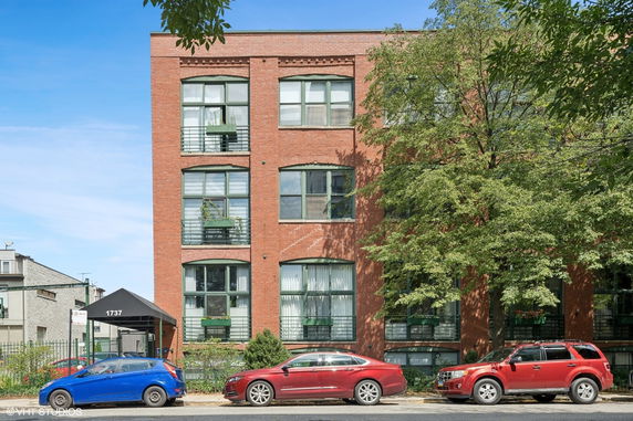 Front view of a multi-story brick building with large windows.