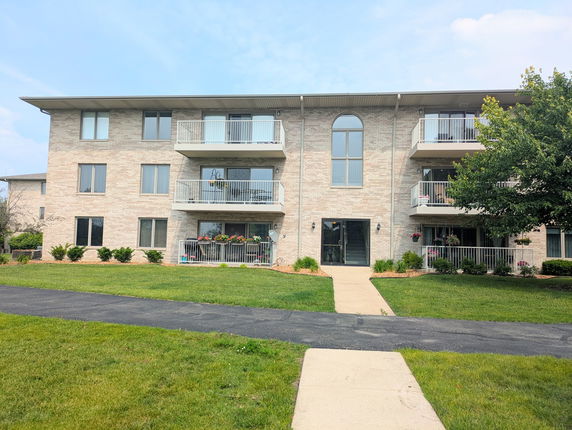 Front view of a three-story apartment building with balconies and a central entrance.