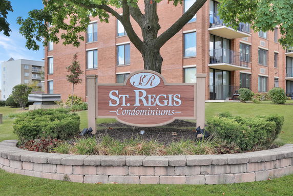 Front view of a multi-story condominium building with balconies and a sign reading 'St. Regis Condominiums.'