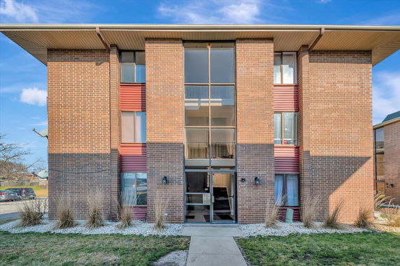Front view of a multi-story brick apartment building with large windows.