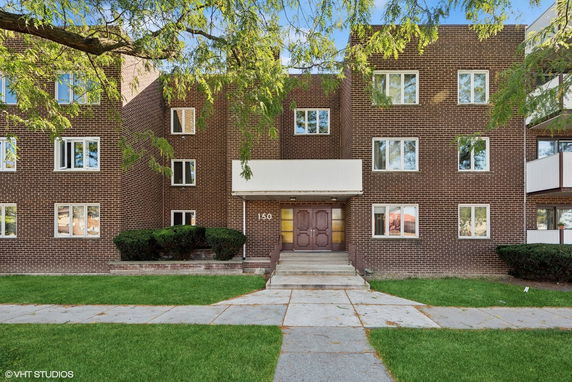 Front view of a multi-story brick building with multiple windows and a central entrance.