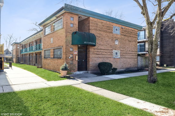 Front view of a low-rise brick apartment building with green awning.