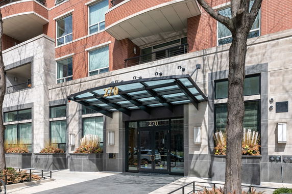 Front view of a multi-story building with a glass-covered entrance and brick facade.