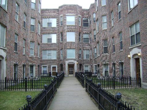 Front view of a brick apartment building with multiple floors and windows.