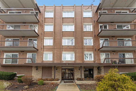Front view of a multi-story brick apartment building with balconies