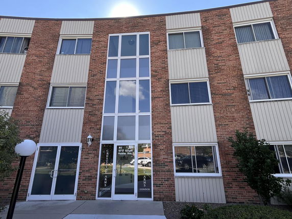 Front view of a multi-story brick building with large vertical glass windows.