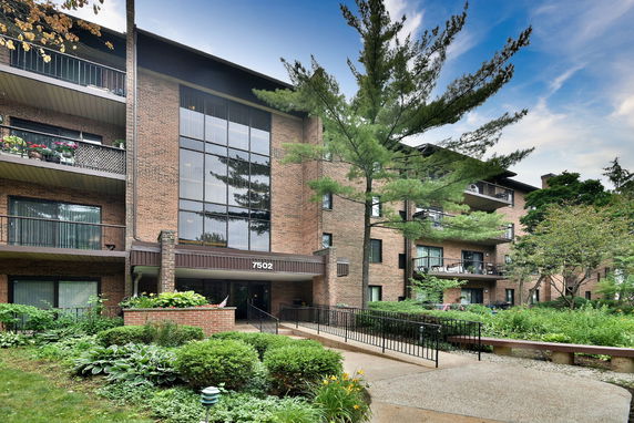 Front view of a multi-story brick building with balconies and large windows.