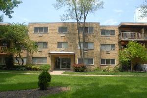 Front view of a three-story apartment building with a brick facade and balconies.