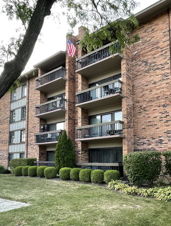 Front view of a multi-story apartment building with balconies and brick exterior.