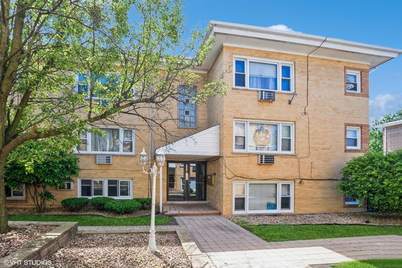 Front view of a multi-story brick apartment building with windows and a small entryway.