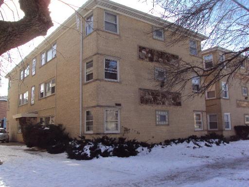 Front view of a multi-story brick apartment building with snow on the ground.