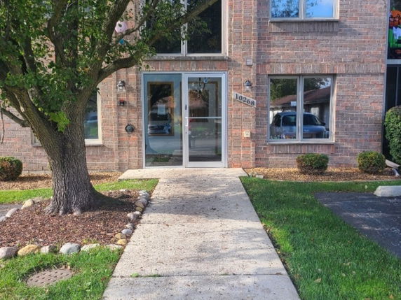 Front view of a brick building entrance with glass doors.