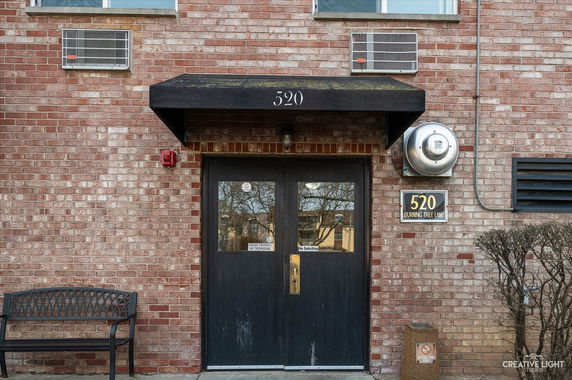 Front view of a brick building entrance with a black awning and double doors.