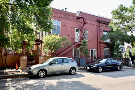 Front view of a two-story red brick building with spiral staircase.