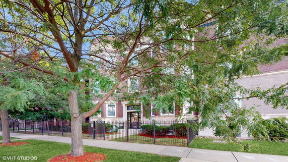 Front view of a brick building with a metal fence and entryway.