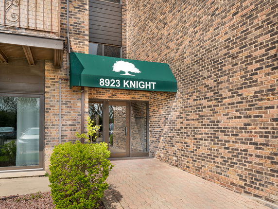 Front view of a brick building entrance with a green awning labeled 8923 KNIGHT.
